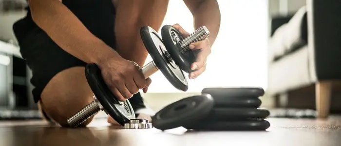 man adding weights to dumbbells