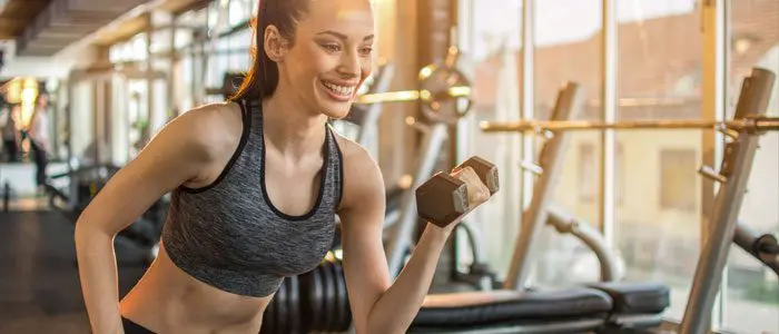 woman doing bicep curls in a gym as a bingo wing exercise