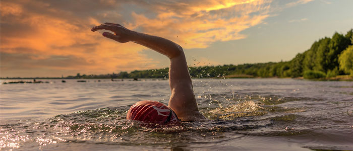 person swimming in a lake outdoors as a way to exercise in the heat